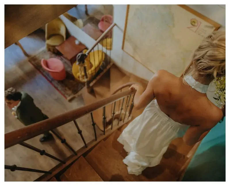 Une autre découverte (ou first look en anglais). La mariée descend l’escalier. Le marié attend pour la voir pour la première fois. Photos prises par un photographe de mariage à Beaune.
